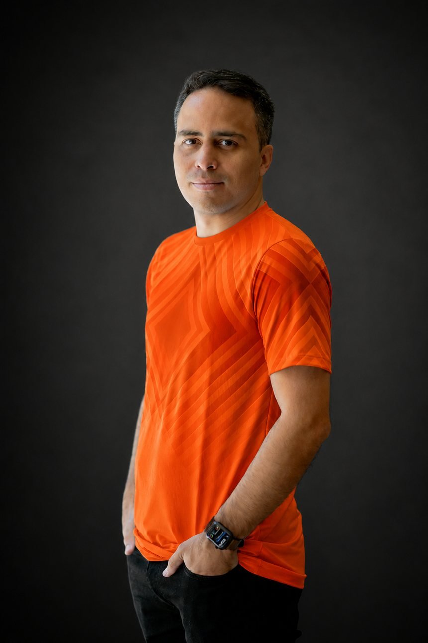 Retrato de Rodrigo Abrahão, web designer, sorrindo em fundo escuro